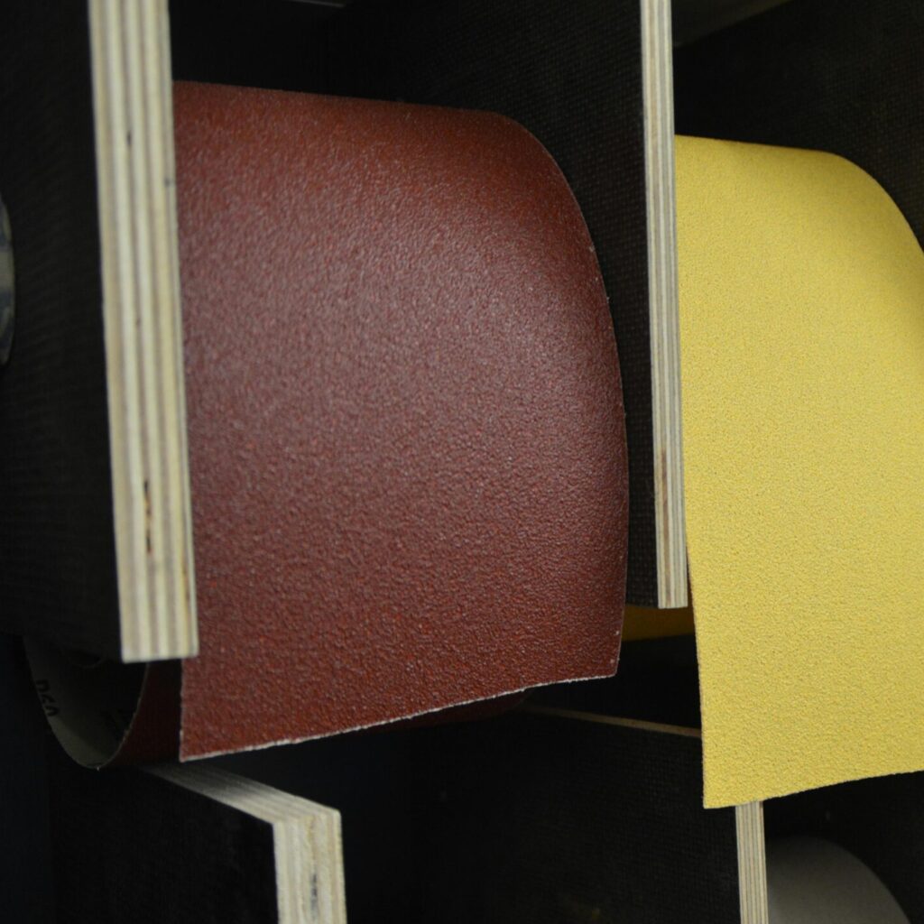 Close-up of colorful sandpaper rolls in an organized storage setup, showcasing different textures.